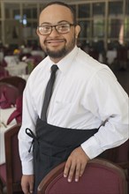 Mixed race server with down syndrome smiling in restaurant