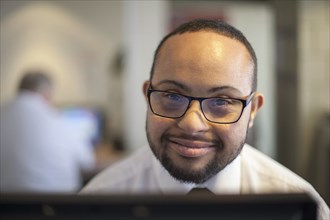 Mixed race businessman with down syndrome working on computer