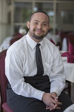 Mixed race server with down syndrome smiling in restaurant