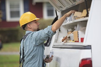 Caucasian worker pulling equipment from truck