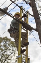 Caucasian cable installer working on ladder