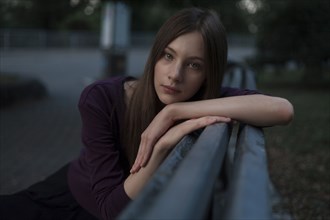 Serious Caucasian woman leaning on bench