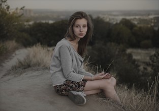 Serious Caucasian woman sitting on hill