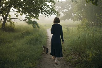 Woman and cat walking on path in fog