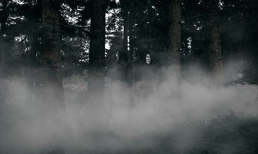 People wearing black robes and white masks in foggy forest