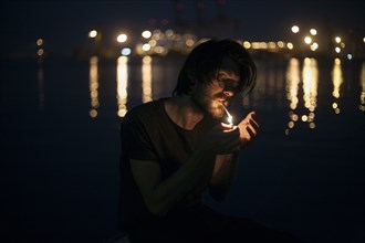 Caucasian man lighting cigarette at waterfront