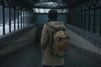 Man standing in tunnel carrying backpack