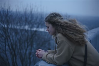 Portrait of pensive Caucasian teenage girl leaning on rooftop