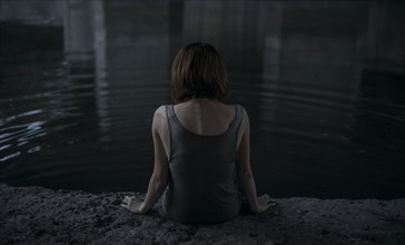 Caucasian woman sitting at edge of water