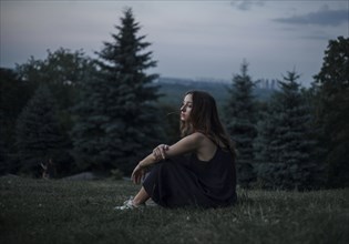 Pensive Caucasian woman sitting in field of grass