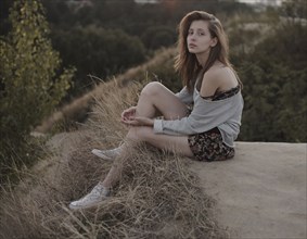 Serious Caucasian woman sitting on hill