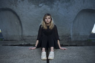 Portrait of serious Caucasian woman sitting on concrete