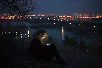Caucasian woman standing near urban waterfront at night