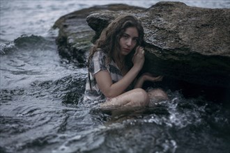 Caucasian girl sitting on rock in ocean