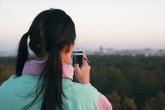 Woman photographing scenic view with cell phone