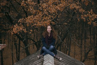 Caucasian woman sitting on roof in autumn