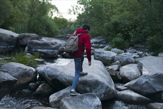 Caucasian man hiking on rocks in river