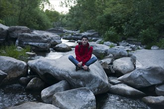 Caucasian man sitting on rock in river