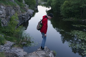Caucasian man standing on rock looking down at river