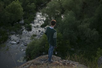 Caucasian man standing on a rock near river
