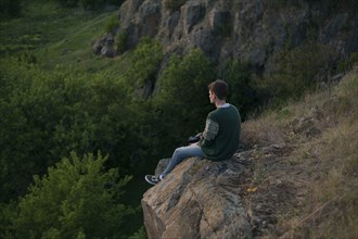 Caucasian man sitting on a rock admiring landscape