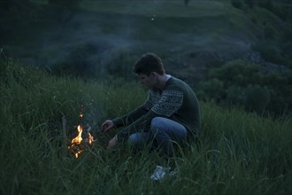 Caucasian man starting campfire at night
