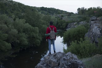 Caucasian hiker standing on rock near river