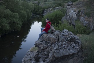 Caucasian man sitting on a rock near river