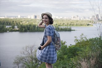 Portrait of a Caucasian woman carrying camera near river