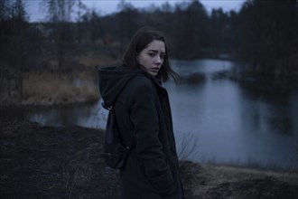Portraits of serious Caucasian woman standing near river at night