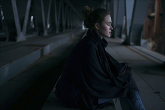 Caucasian woman sitting under bridge