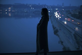 Caucasian woman standing near waterfront at night