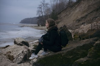 Caucasian woman sitting on rocks near ocean