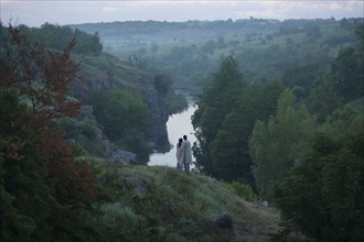 Caucasian couple standing on hill admiring river