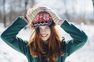 Caucasian woman holding hat on head in winter