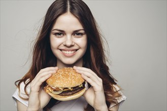 Smiling Caucasian woman holding cheeseburger