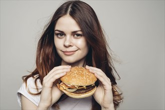 Grinning Caucasian woman holding cheeseburger