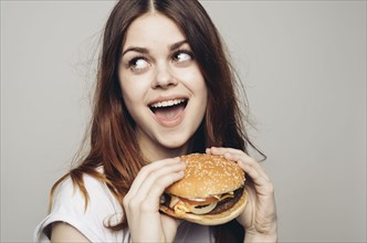 Surprised Caucasian woman holding cheeseburger