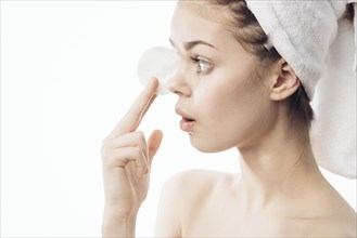 Surprised Caucasian woman cleaning skin with pad
