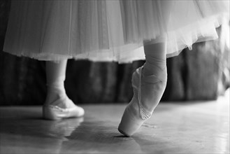 Legs of woman stretching in ballet shoes