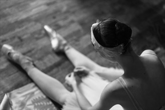 Woman sitting on floor wearing ballet shoes