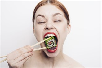 Caucasian woman eating sushi with chopsticks