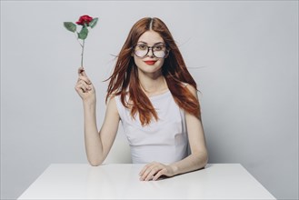 Caucasian woman sitting at windy table holding rose