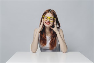 Laughing Caucasian woman sitting at table wearing yellow eyeglasses