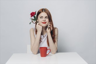 Caucasian woman sitting at table holding rose talking on cell phone