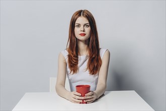 Caucasian woman sitting at table holding red cup