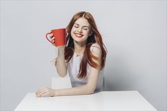 Caucasian woman sitting at windy table holding red cup
