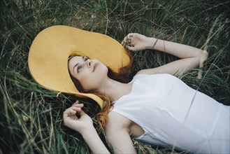 Caucasian woman wearing hat laying in grass