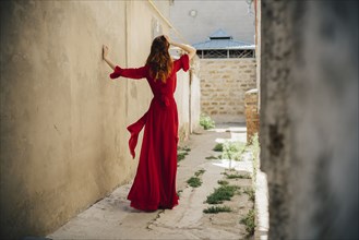 Caucasian woman wearing red dress in alley
