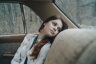 Caucasian woman in back seat of car looking out window